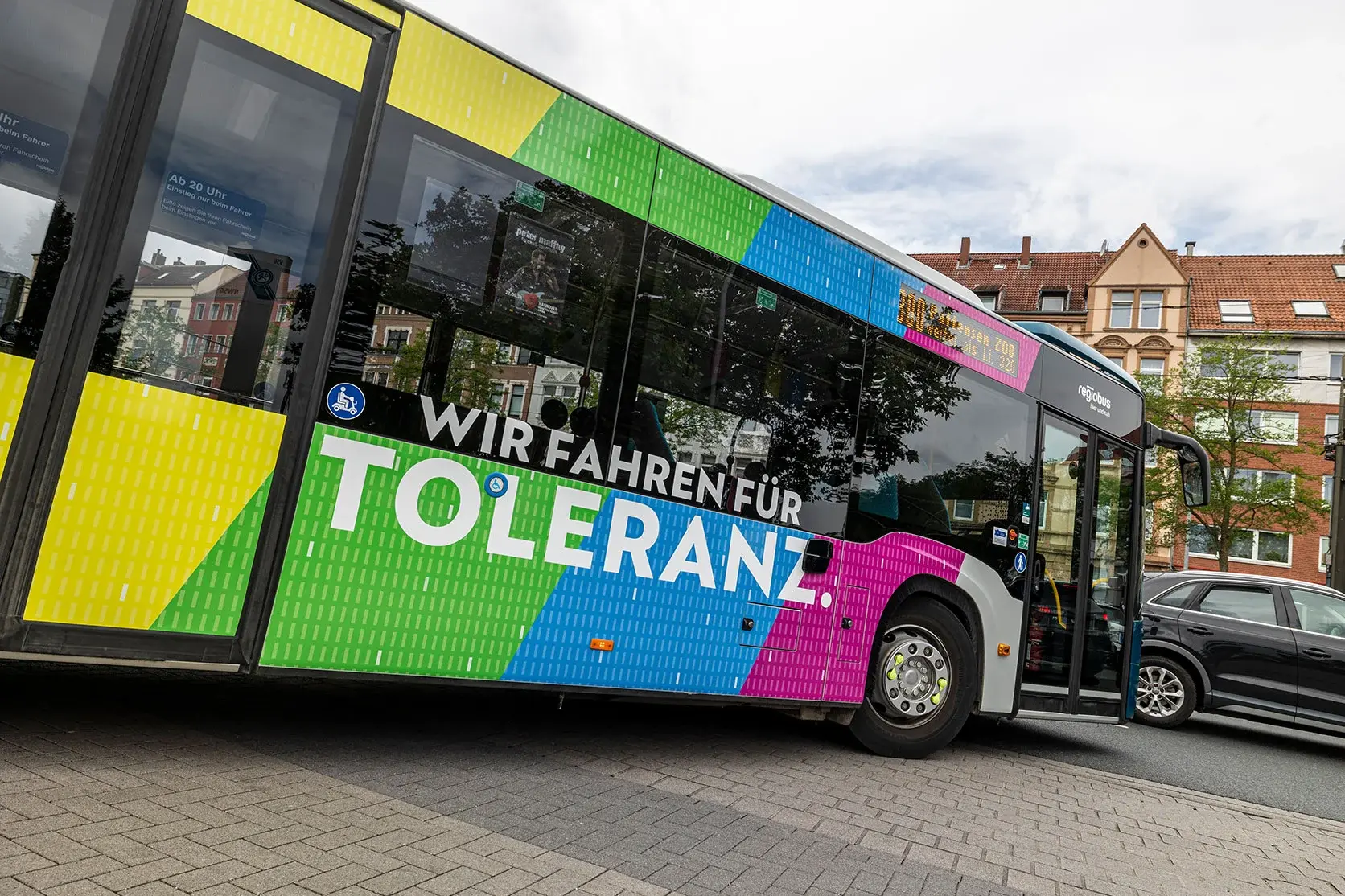 Ein Linienbus mit diagonalen Streifen in verschiedenen Farben und der Aufschrift: 'Wir fahren für Toleranz.'